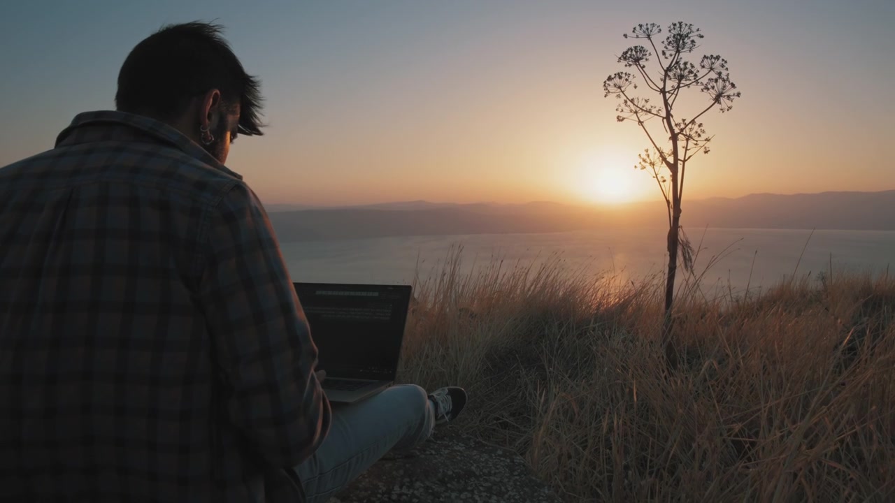 A young man working on a laptop outdoors