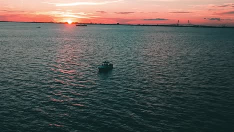 small boat in the ocean at sunset from drone view