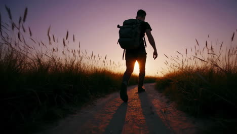 man hiking on a path at sunset