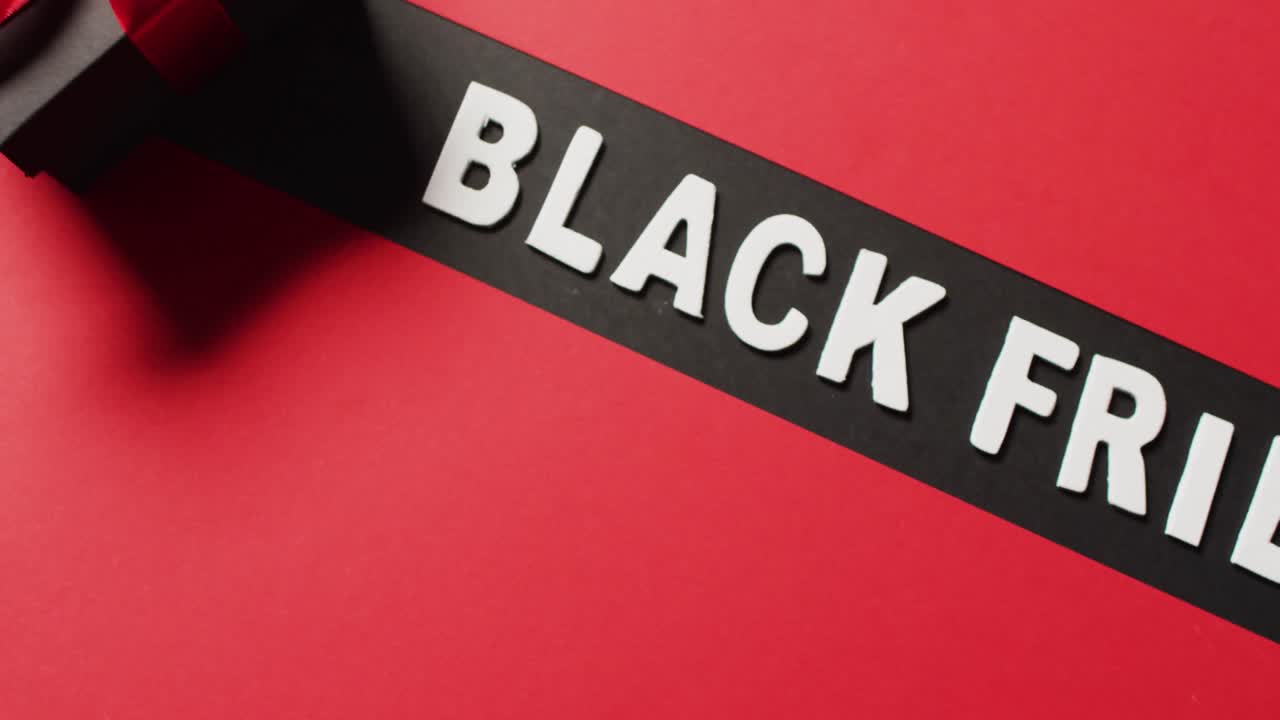 texto del viernes negro en blanco sobre franja negra y caja de regalo negra con cinta roja, sobre fondo rojo