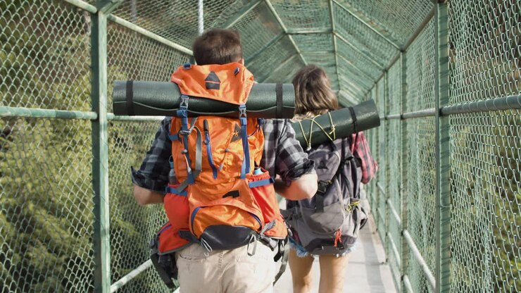 Pareja de viajeros caminando por un puente sobre un precipicio