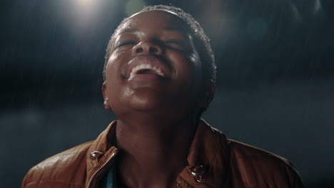 portrait happy african american woman in rain smiling enjoying playful freedom having fun celebrating passion for life on rooftop at night