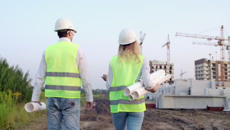 ingeniero y técnico en el sitio de construcción revisando planos de oficina y dibujos técnicos caminando y discutiendo.