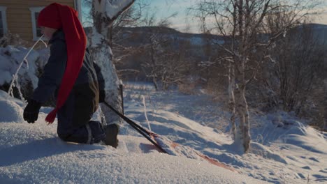 un niño tirando de su led cuesta arriba en la nieve hasta la rodilla durante la navidad en noruega