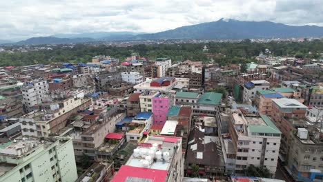 toma aérea de un edificio con montañas en el fondo con árboles y nubes en india