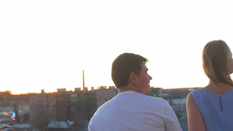 romantic couple on the balcony look at the city at sunset