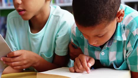 Escolares-Leyendo-Un-Libro-En-La-Biblioteca-De-La-Escuela