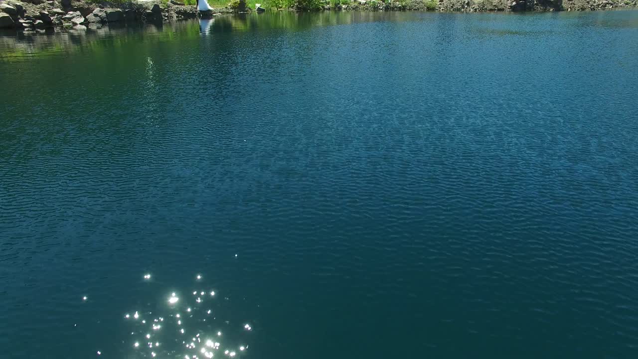 Groom And Bride Hugging Outdoor. Aerial shot of a groom and bride on river bank at romantic moment