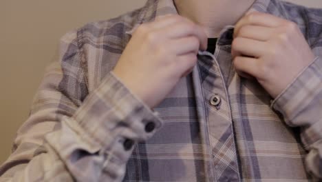 buttoning up a long sleeved plaid shirt