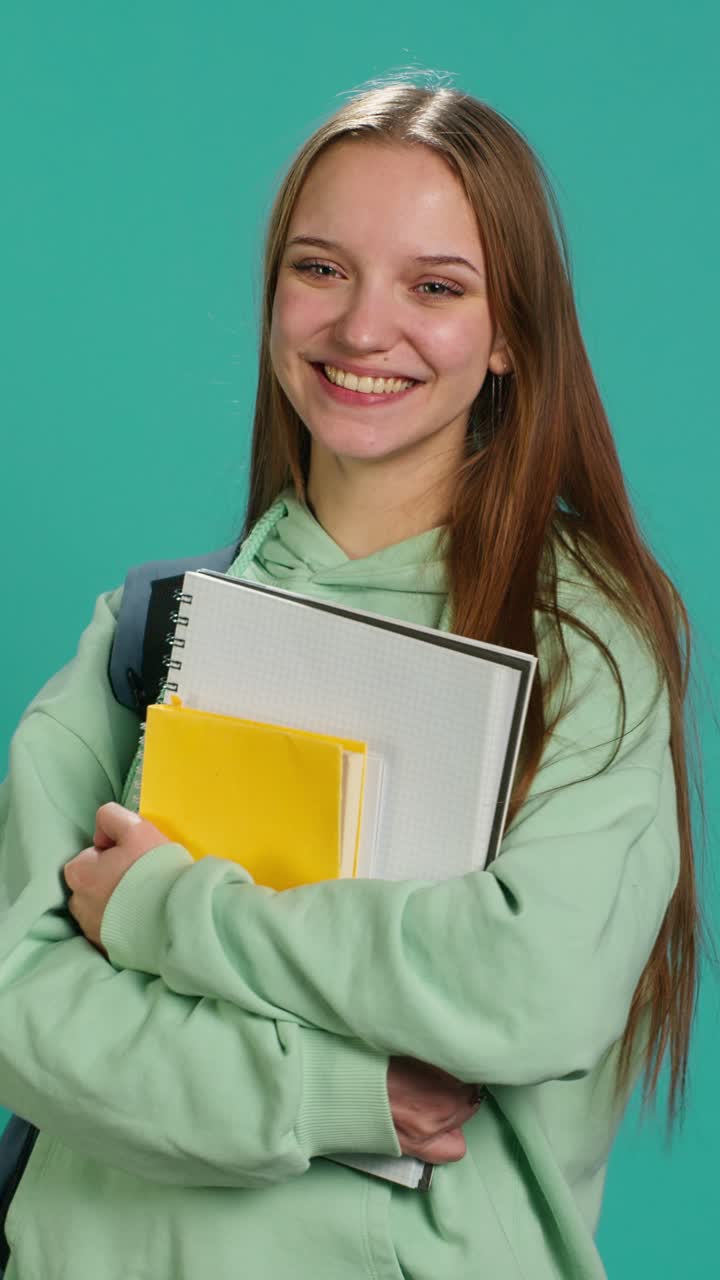 Video verticale con ritratto di uno studente allegro con materiale scolastico tra le braccia