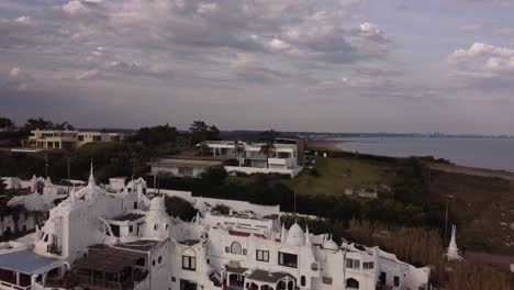 Aerial-shot-of-tourist-bus-arriving-top-of-hill-in-Punta-Ballena-Area-with-white-luxury-houses