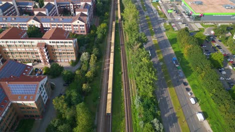 Breathtaking-aerial-top-view-flight-Yellow-suburban-train-S-Bahn-on-tracks,-Berlin-Marzahn-summer-2023