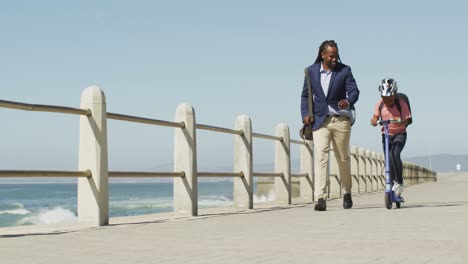 video of happy african american father and son on scooter spending time by sea