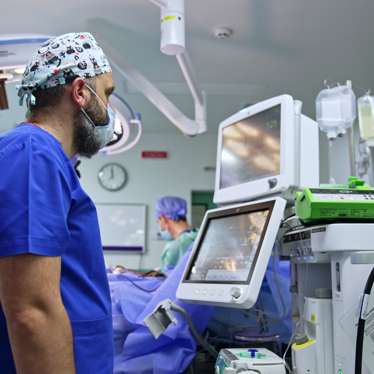 Male anesthesiologist looks attentively on the monitors showing the life signs of a patient under surgery. Doctor presses the button on the apparatus