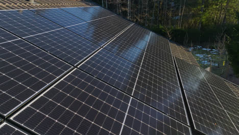 Reflecting-PV-array-on-a-self-sufficient-house-roof,-spring-day---reverse,-drone-shot