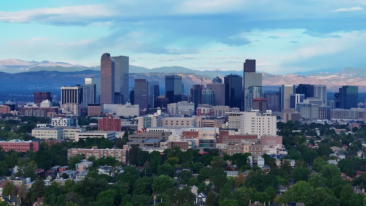 Grattacieli del centro di Denver incorniciati da alberi e cime distanti, avvicinamento aereo