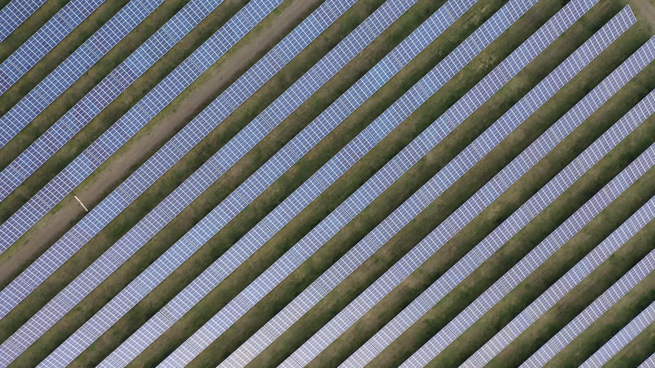 Aerial drone view into large solar panels at a solar farm at bright sunset