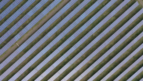 aerial drone view into large solar panels at a solar farm at bright sunset