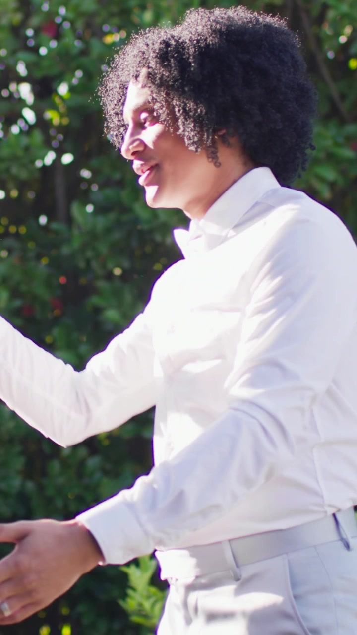 Vertical video: Shielding eyes man in bowtie spotting approach gesturing shaking hands ring in yard