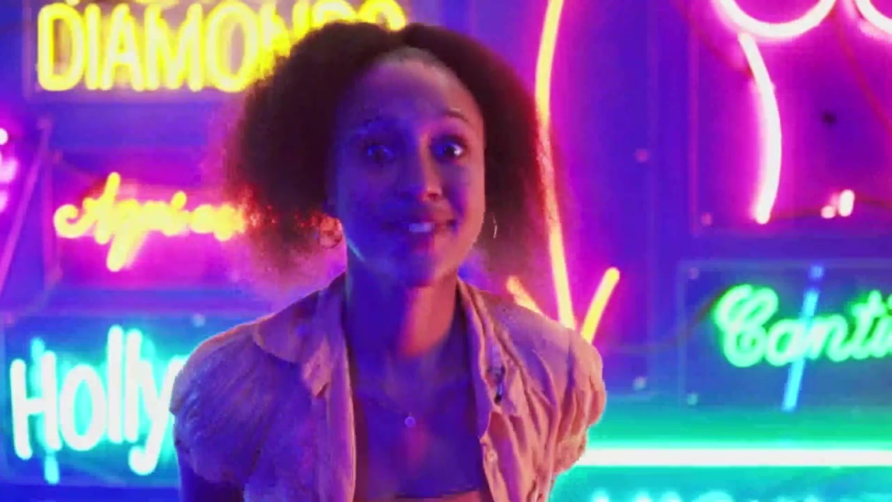 Giovane donna felice che balla davanti a vivaci insegne al neon