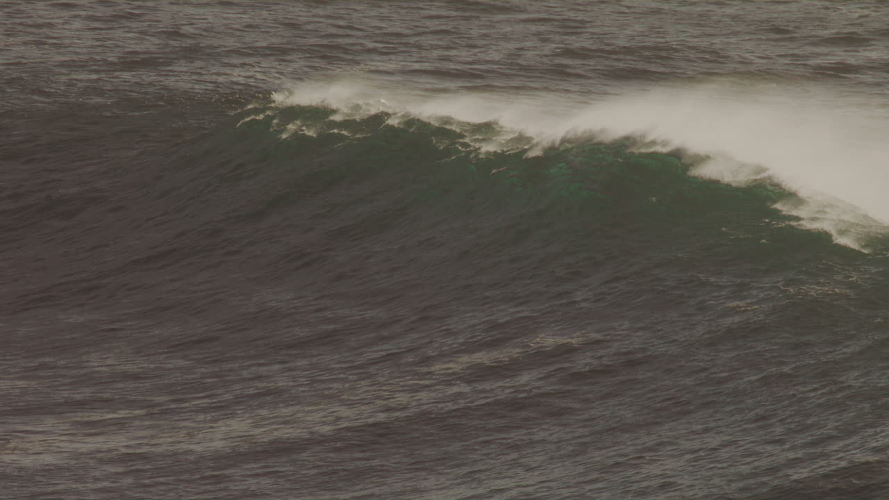 Huge Avalon wave captured in slow motion as golden sunlight illuminates spray and water texture
