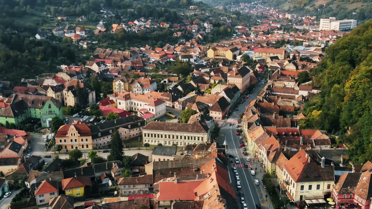 Aerial drone view of Sighisoara, Romania. Roads with cars, greenery and buildings