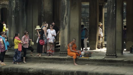 buddhism monks in orange garb and tourists in the ancient temple angkor wat.