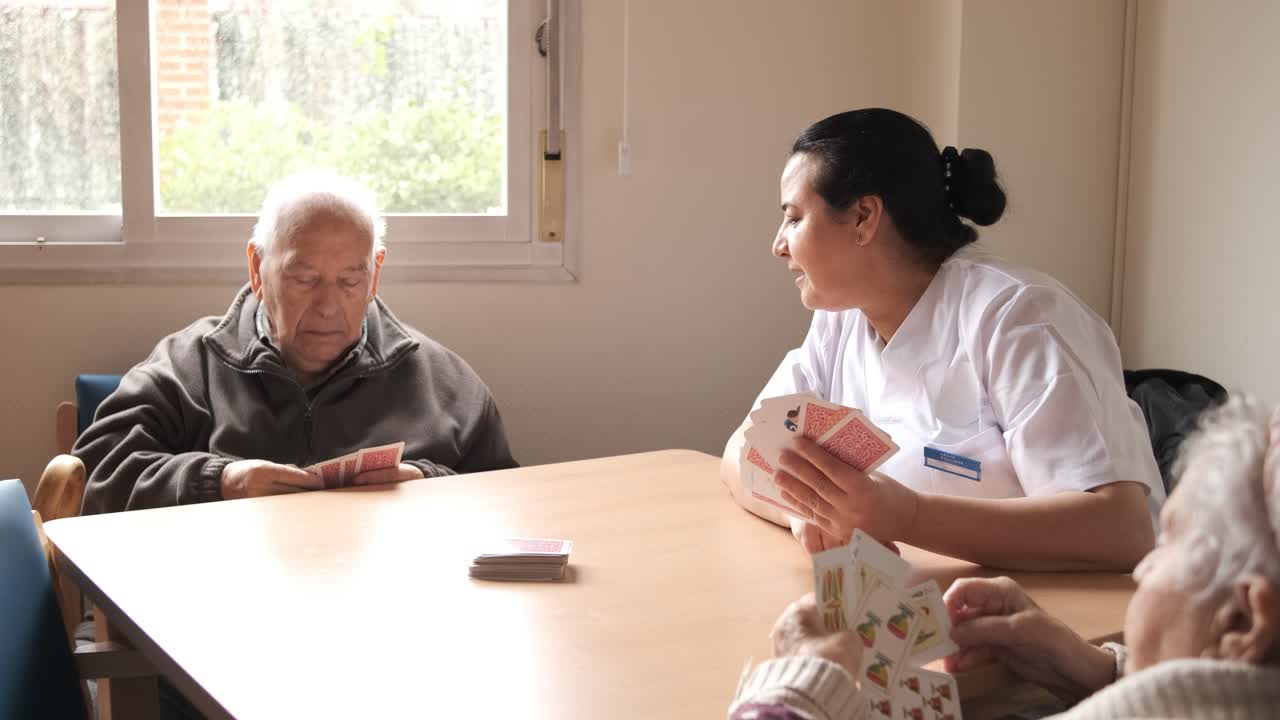 Female caregiver playing cards with elderly men rehabilitation center