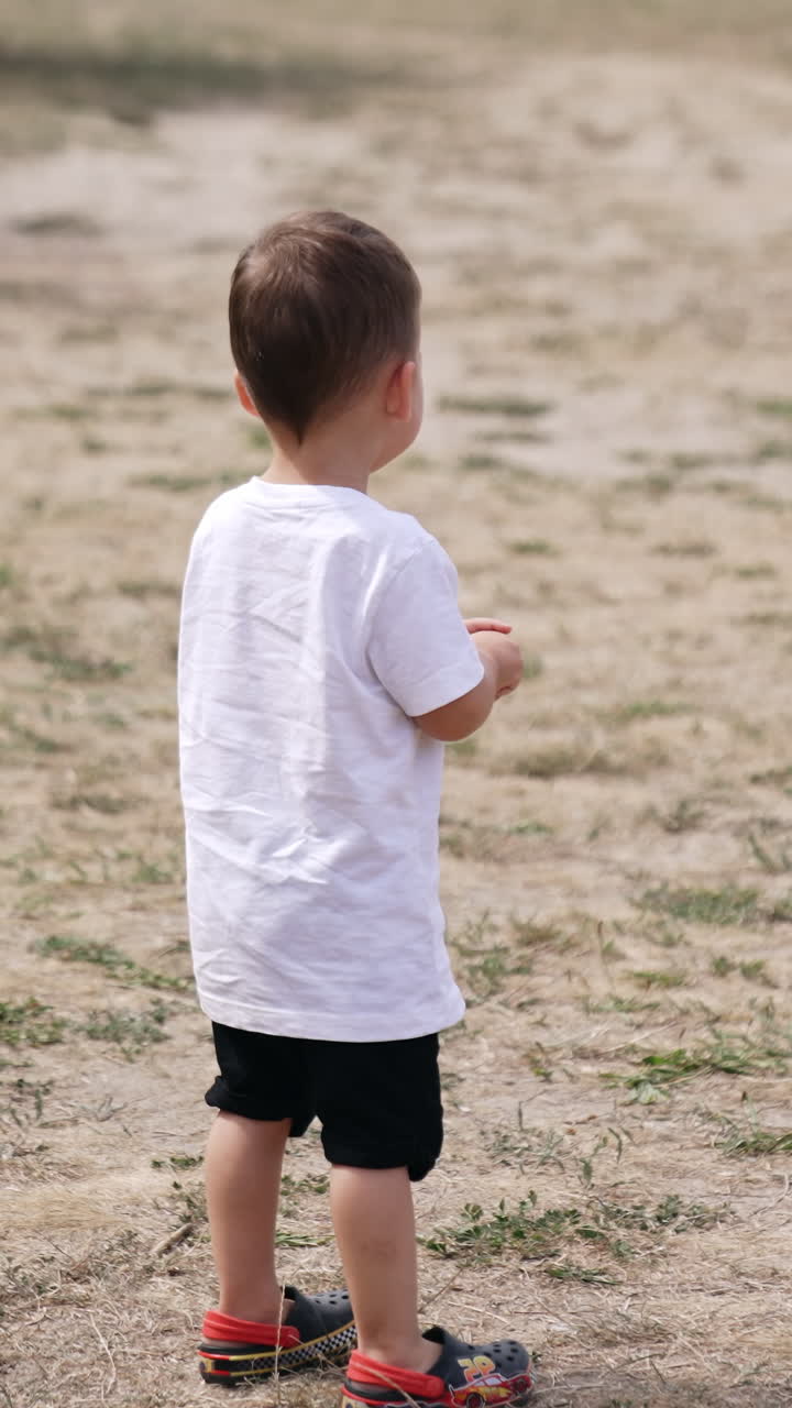Playing outdoor in park small child. Baby boy playing in the park. Vertical video