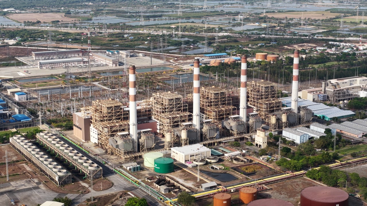 Aerial footage capturing a large thermal power plant with its towering chimneys and extensive infrastructure, illustrating the scale of industrial electricity generation and energy production