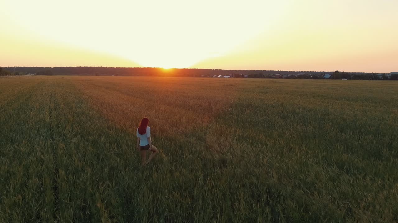 mujer caminando por un campo de trigo al atardecer