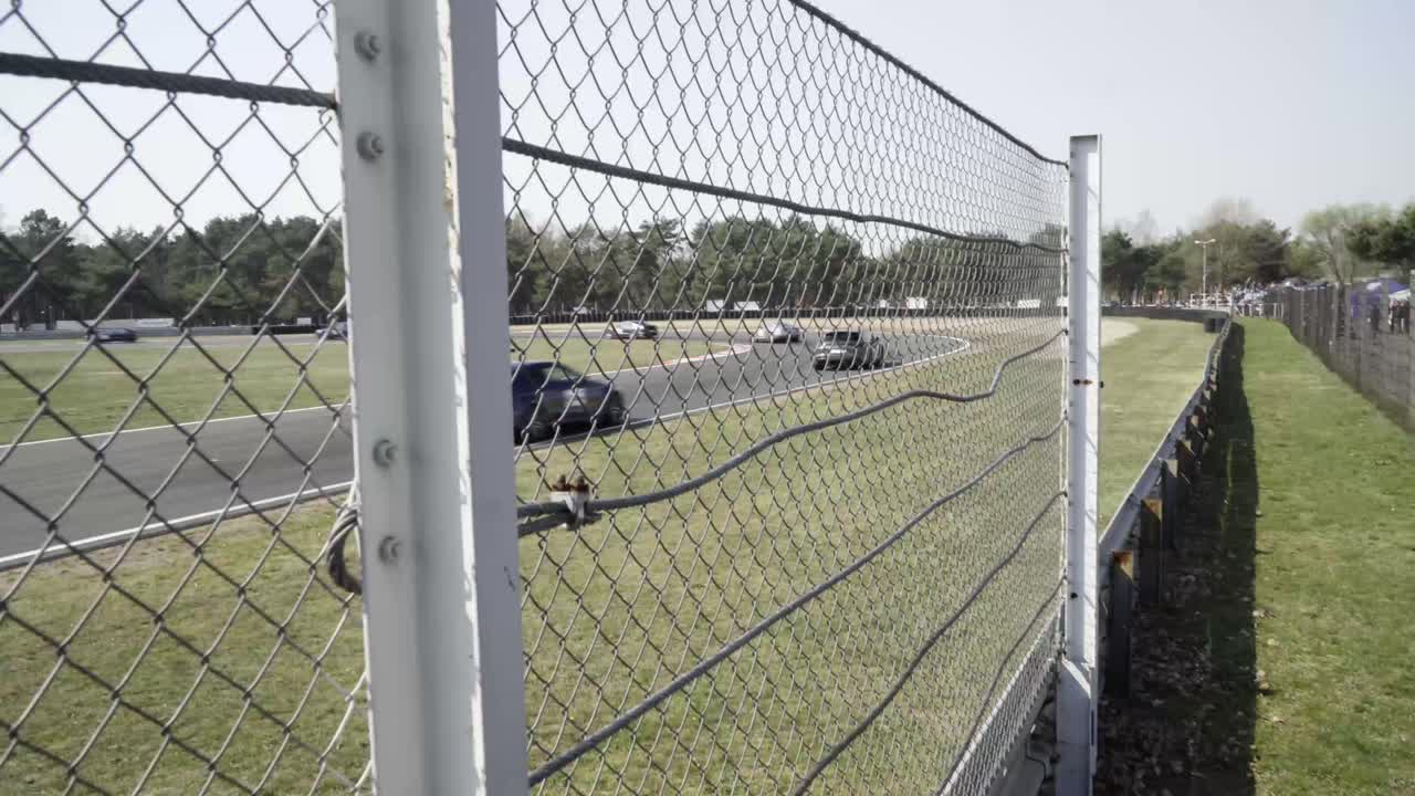 Big group of modern fast race super cars driving on the professional racet track during track day view from behind the fence crowd in 4K