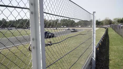 big group of modern fast race super cars driving on the professional racet track during track day view from behind the fence crowd in 4k