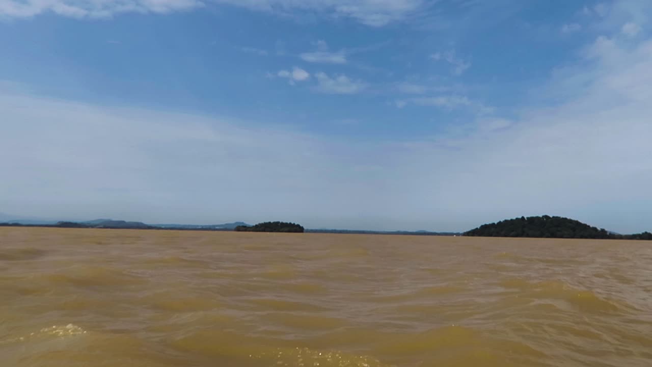brown river with waves and mountains in the background under a blue sky with clouds in Ethiopia.