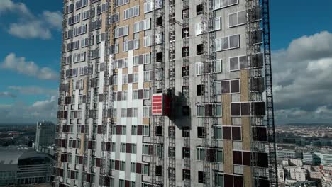 Construction-elevator-descending-on-exterior-wall-of-skyscraper,-La-Defense,-Paris-in-France