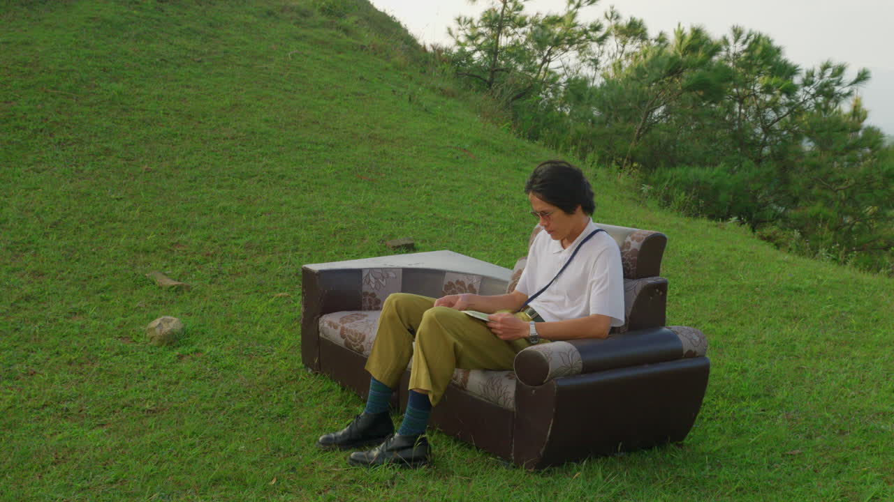 오래된 빈티지 레트로 소파 소파에서 야외에 앉아서 책을 읽는 젊은 아시아 남성 학생