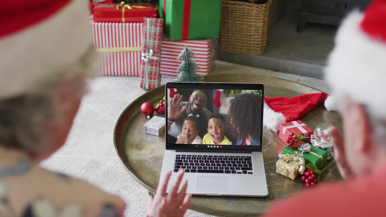 pareja caucásica de alto nivel usando una computadora portátil para una videollamada de navidad con familia feliz en la pantalla