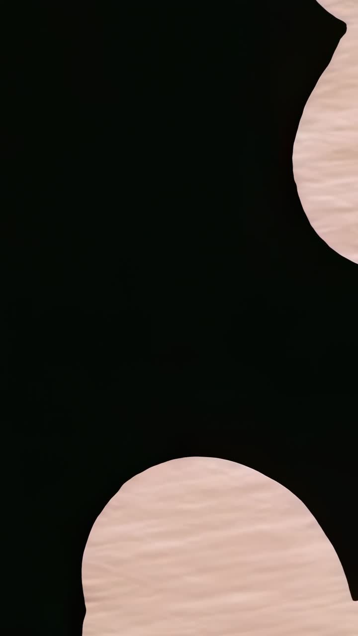 Vertical video: After two seconds, two beige cloud shapes fading off black canvas, copy space