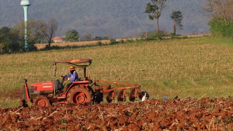 agricultural tractor tilling soil in rural landscape