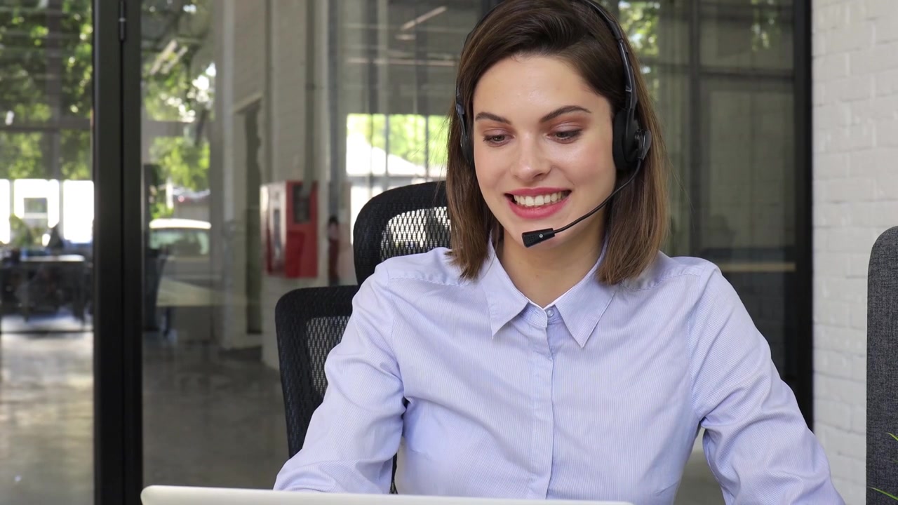 Atendente de atendimento ao cliente sorrindo e falando em fones de ouvido no escritório
