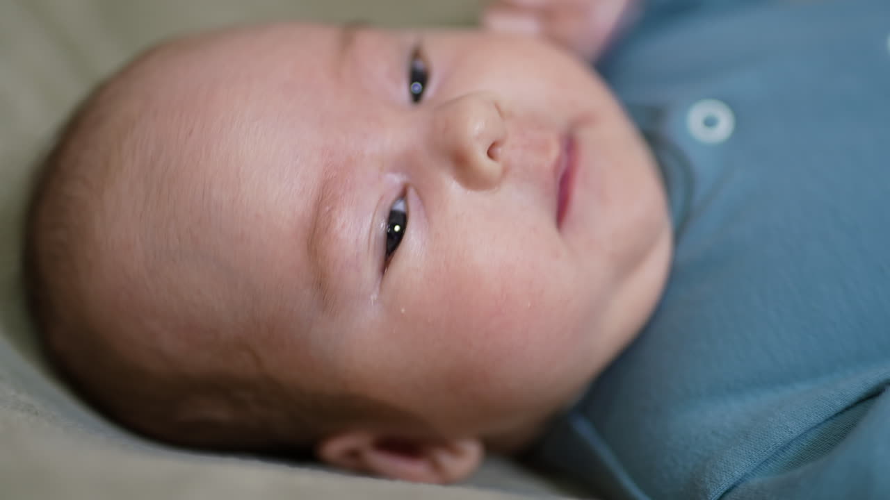 Lovely baby face with plump rosy cheeks. Cute baby boy lying his head turned right yawning sweetly in front of camera. Close up.