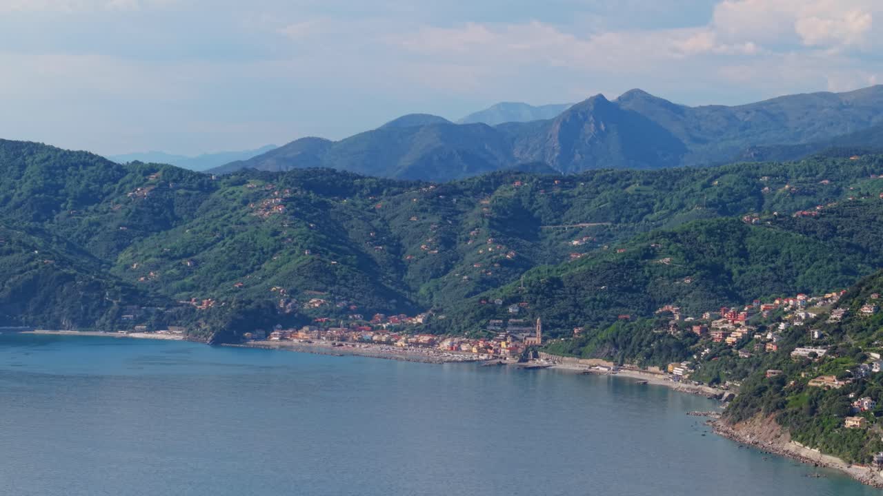 Splendida vista costiera di un borgo italiano, con colline lussureggianti e acqua cristallina sotto un cielo soleggiato.