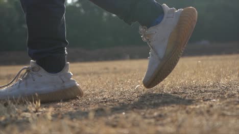 Gehen-Sie-Mit-Dem-Schuh-Auf-Trockenem-Gras-Eine-Filmische-Aufnahme-Im-Gegenlicht