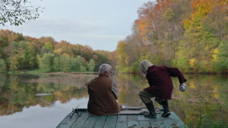 grandfather and grandchild fishing by a lake in autumn