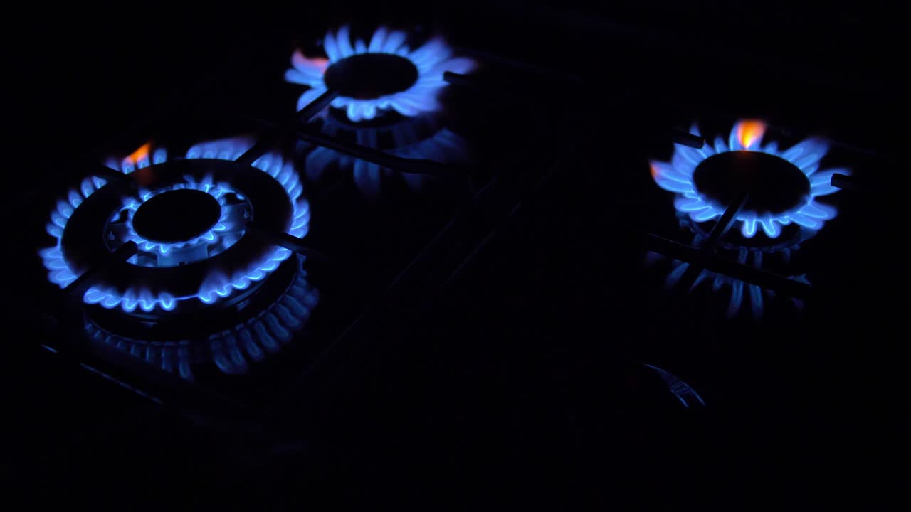 가스 스토브가 켜지고 꺼지고 파란 불꽃이 어 속에서 불타고 있습니다.