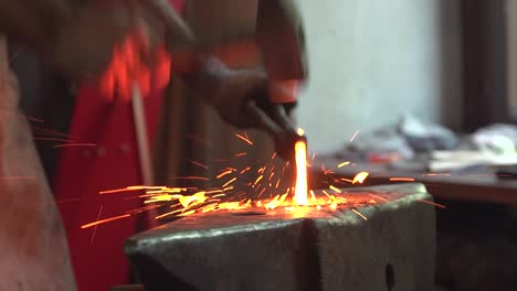 smith working on an anvil with a hot piece of metal and a hammer shaping