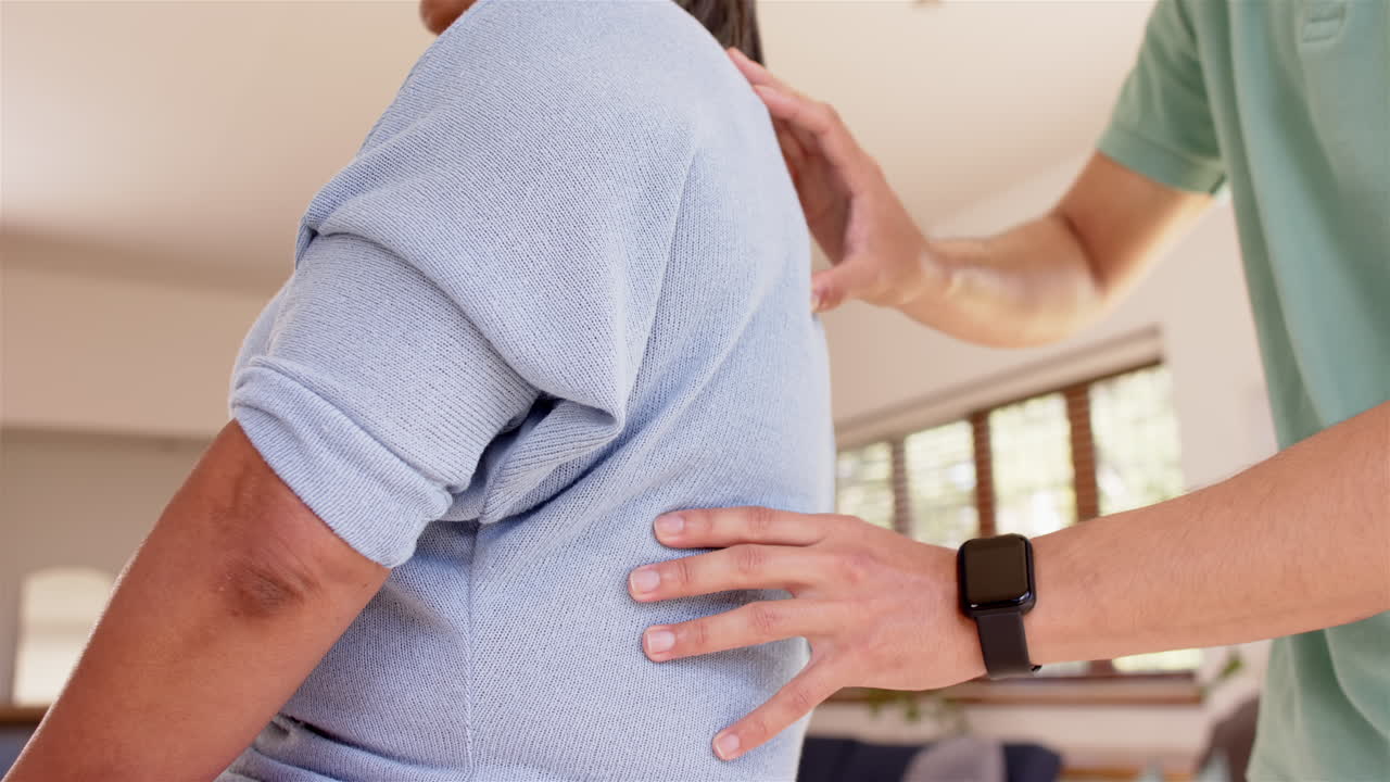 Physiotherapist assisting senior woman with back exercises during therapy session