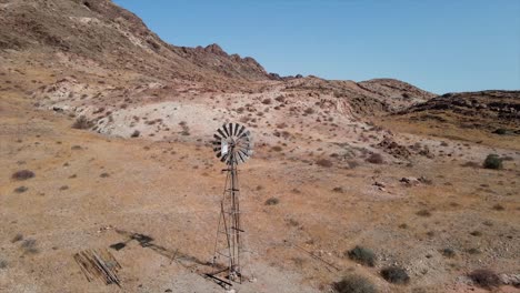 An-old-wind-pump-rotating-on-a-dry-and-desolate-piece-of-farm-land-in-Namibia