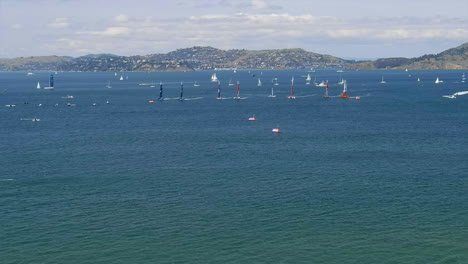 aerial view panning across san francisco sailing grand prix as many boats navigate at speed under mountain landscape