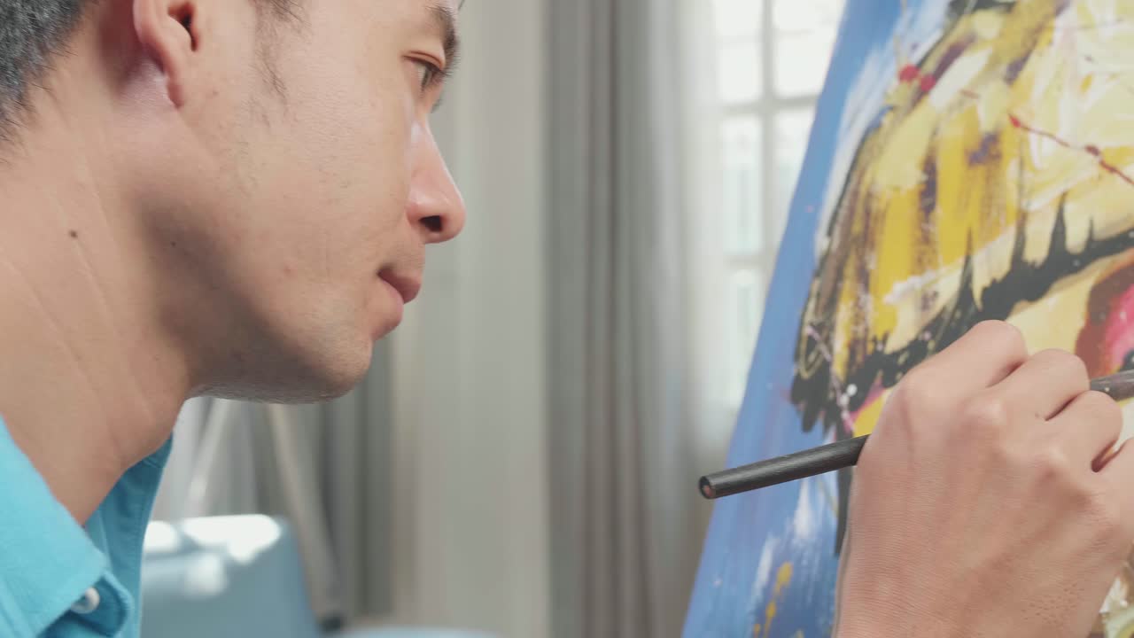 Close Up Side View Of An Asian Artist Man Holding Paintbrush Mixed Colour And Thinking Before Painting A Girl'S Face On The Canvas